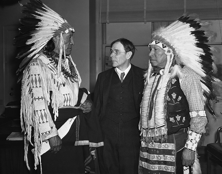De izquierda a derecha Pájaro Dewie y Jaime-Pipa-en-la-Cabeza, supervivientes de la masacre de Wounded Knee, SD  son recibidos por un funcionario del Gobierno de los EEUU en Washington, DC el 4 de marzo de 1938,  compareciendo para solicitar indemnizaciones por la matanza.  Foto: Associated Press.